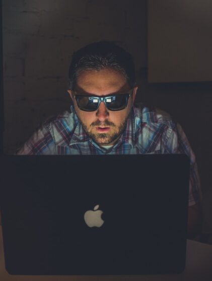 man wearing sunglasses using MacBook